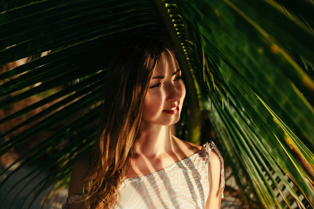 muotokuva houkutteleva tyttö alla iso vihreä palmu lehtiä
 - Valokuva, kuva