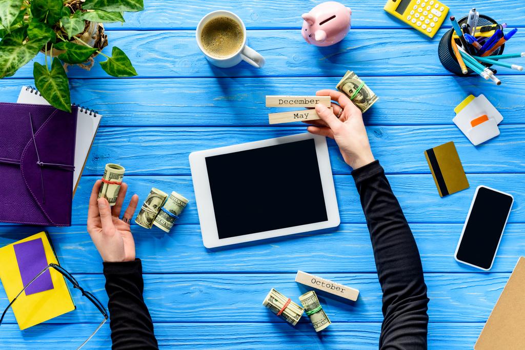 Concepto de gastos de planificación con persona de negocios con calendario y dinero en mesa de madera azul
 - Foto, imagen