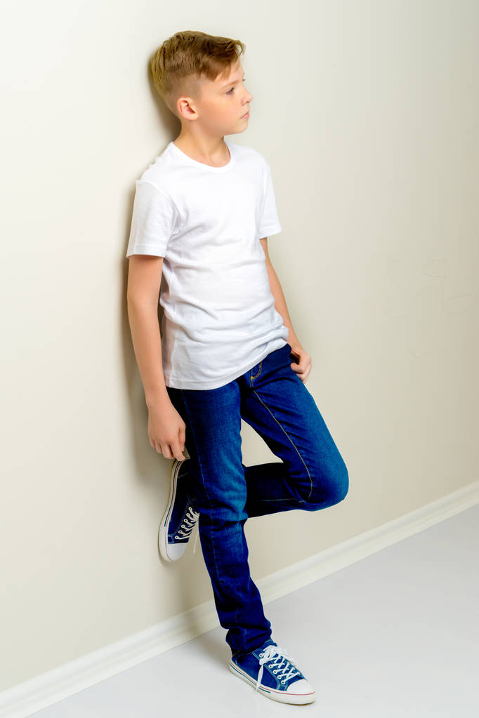 A divatos iskolás korú fiú nekidőlt a fal. - Fotó, kép