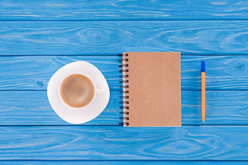 вид на чашку кофе, учебник и ручку на синих деревянных досках
 - Фото, изображение