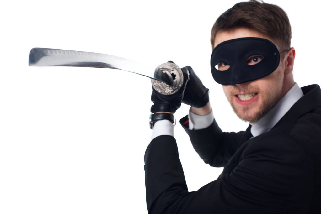 Portret van emotionele spion agent in masker en handschoenen met katana geïsoleerd op wit - Foto, afbeelding