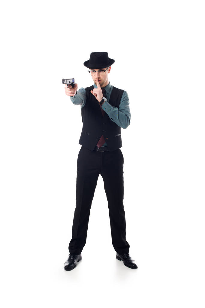 Spion mit Hut und Brille, Waffe in der Hand, Schweigezeichen auf weißem Grund - Foto, Bild
