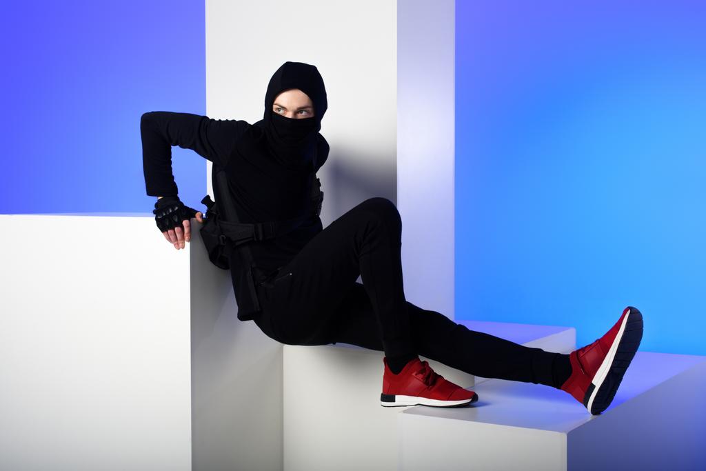 ninja em roupas pretas em pé sobre blocos brancos isolados em azul
 - Foto, Imagem