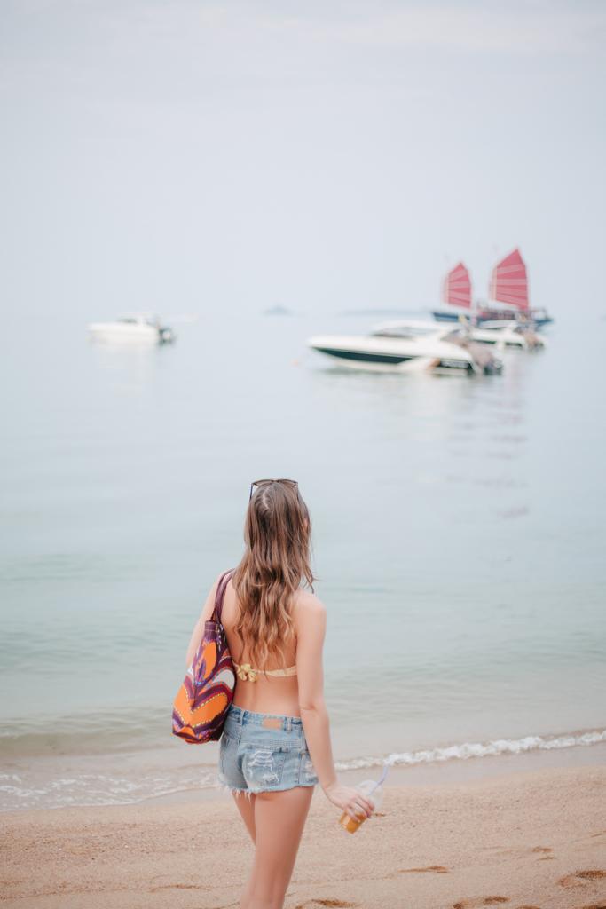 peruutusnäkymä naiselle, jolla on cocktail ja katselee veneitä merellä
 - Valokuva, kuva