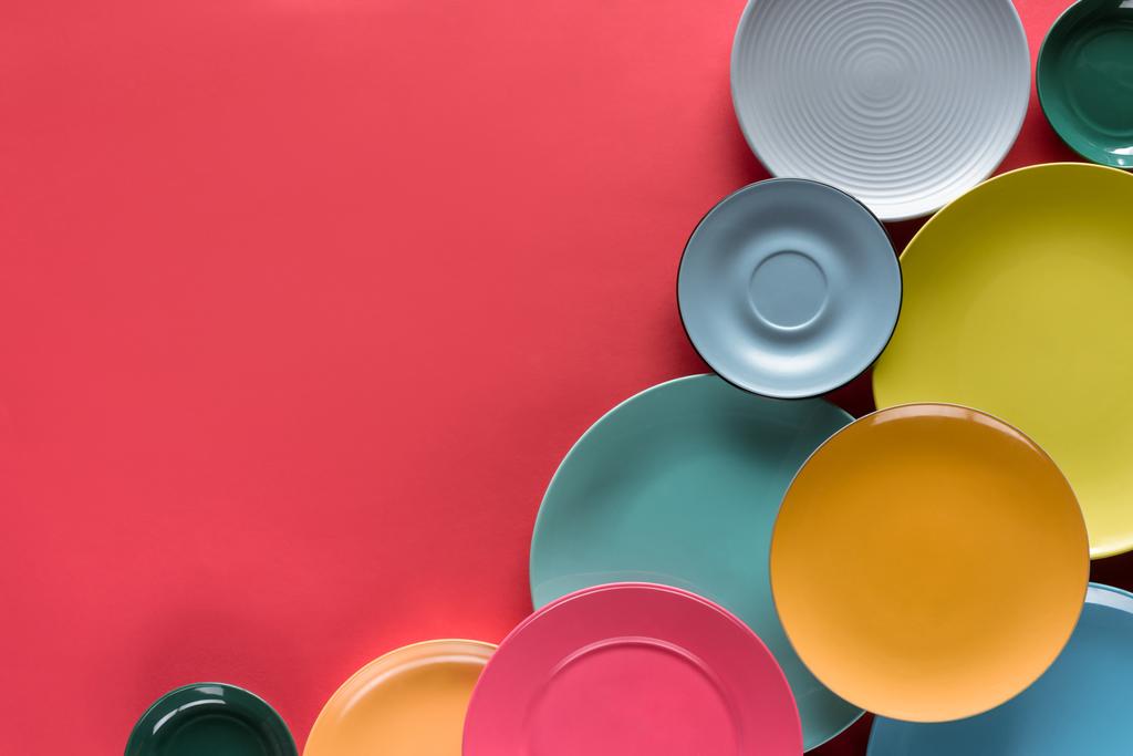 Σύνθεσης των πολύχρωμα πιάτα σε κόκκινο φόντο - Φωτογραφία, εικόνα