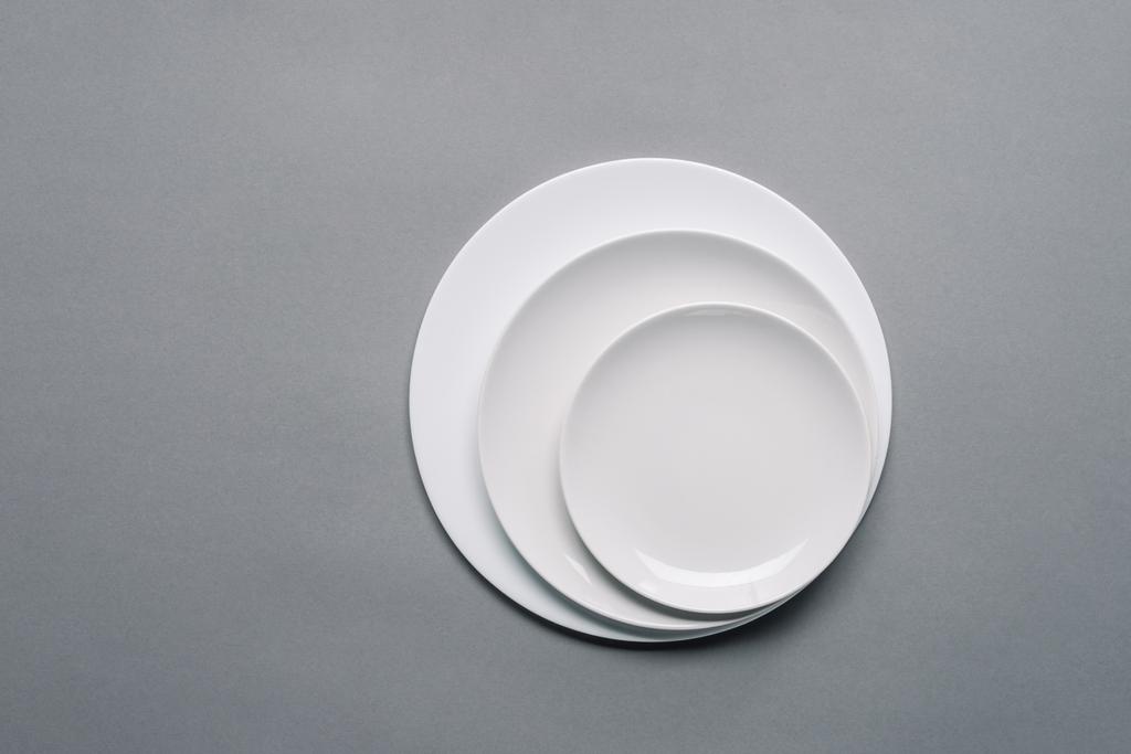 Farklı boyutlarda gri arka plan üzerinde beyaz tabaklar - Fotoğraf, Görsel