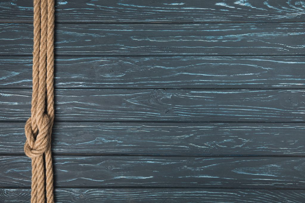 κάτοψη του φόντου με καφέ ναυτικά σχοινί με κόμπο σε ξύλινες σανίδες - Φωτογραφία, εικόνα