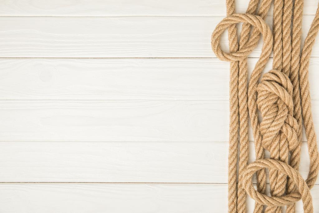 top view of brown nautical knotted ropes on white wooden background - Photo, Image
