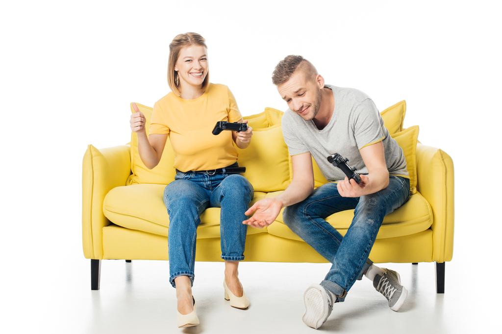 couple on yellow sofa playing video game together isolated on white - Photo, Image