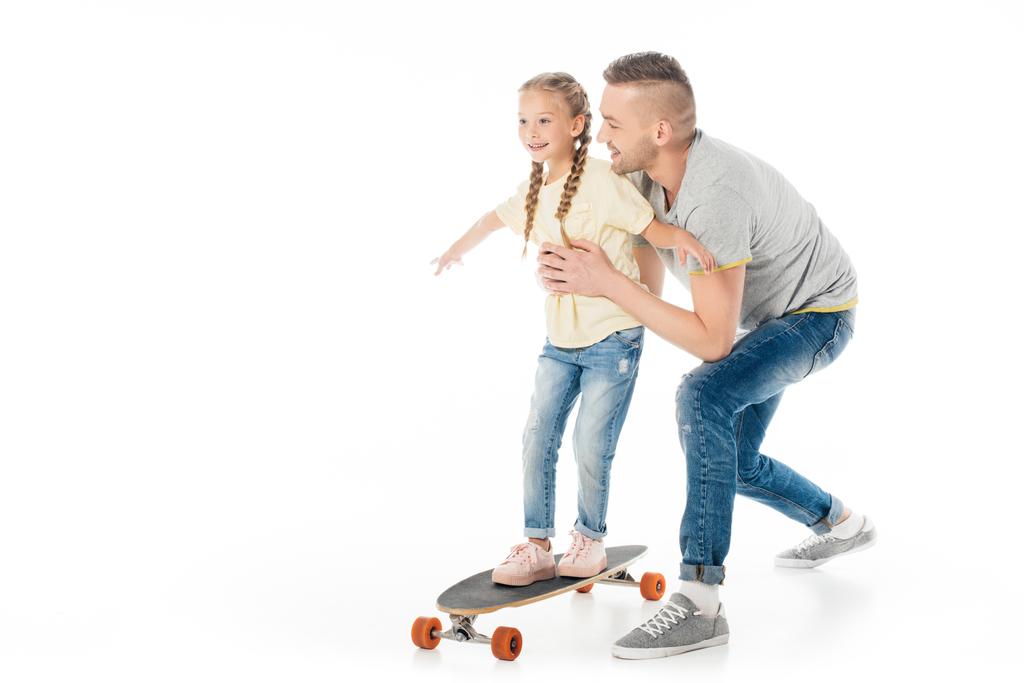 father helping little daughter skating on skateboard isolated on white - Photo, Image
