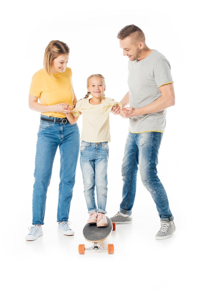 usmívající se rodina drží ruce malou dceru na skateboard izolované na bílém - Fotografie, Obrázek