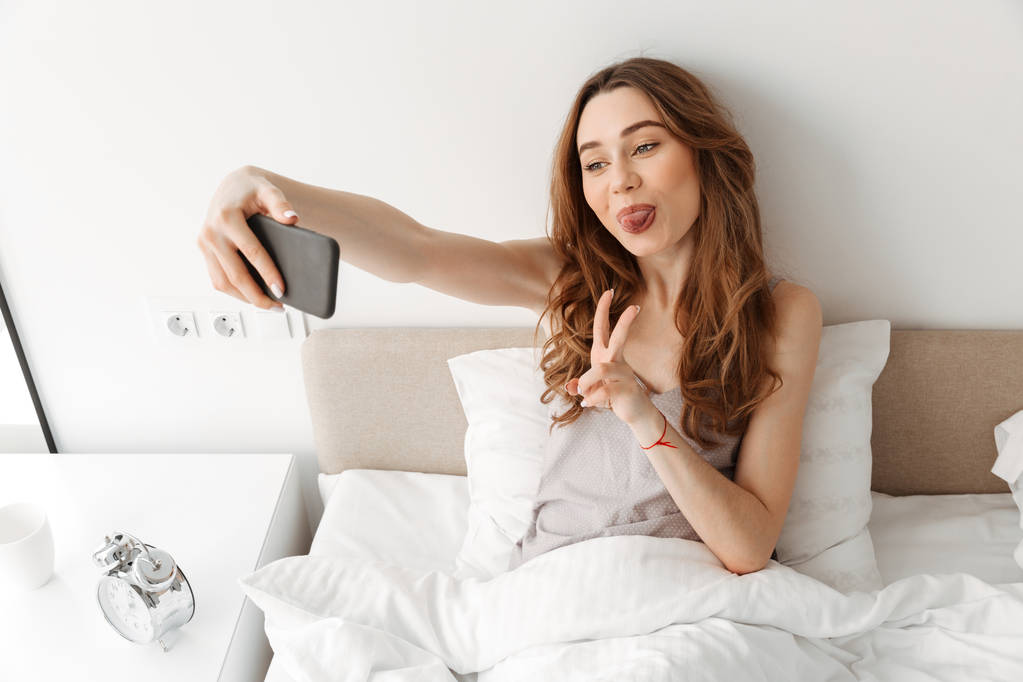 Portrait de femme amusante se reposant au lit après avoir dormi avec du blanc
  - Photo, image