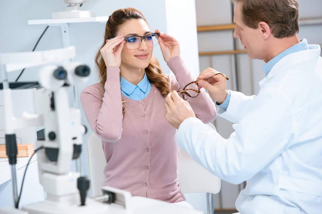 oftalmólogo ayuda al paciente a elegir gafas con lentes necesarias en la clínica
 - Foto, imagen