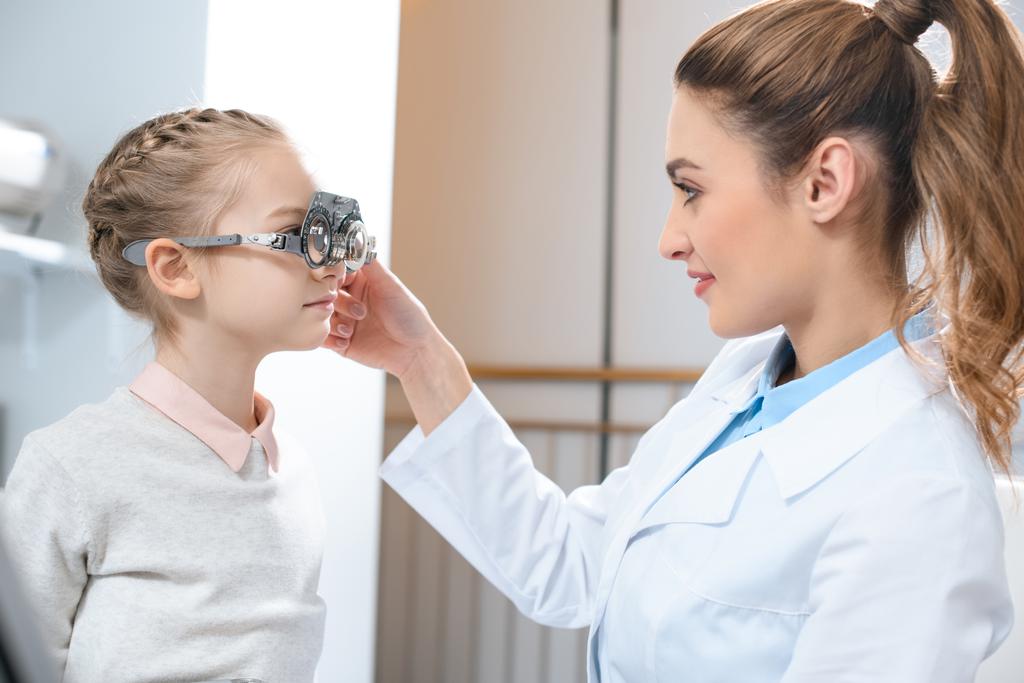 optometrist examining kid eyes with trial frame in clinic - Photo, Image