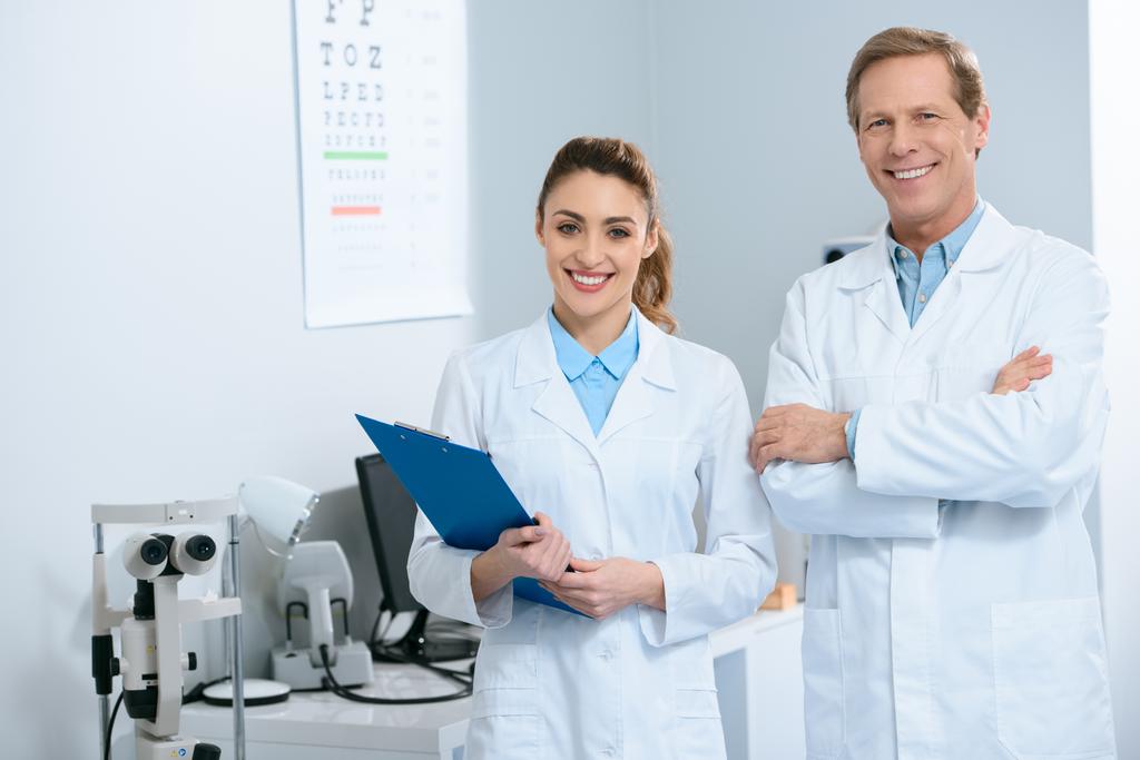 smiling ophthalmologists standing with diagnosis in clinic  - Photo, Image