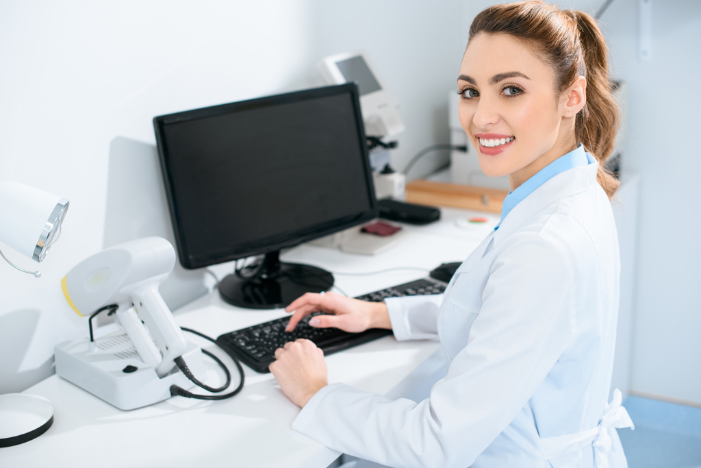 привабливий жіночий офтальмолог, що працює з комп'ютером у клініці
 - Фото, зображення