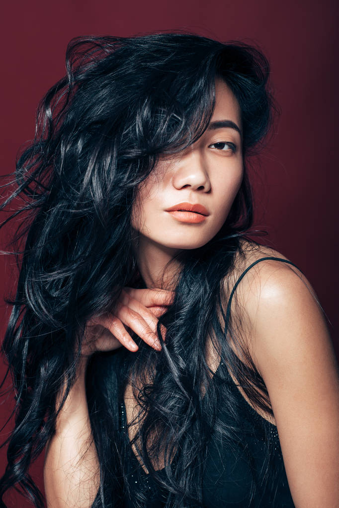 Piękne Azjatki kobiety portret na brązowym tle. Orientalne modelu z długie kręcone włosy na studio - Zdjęcie, obraz