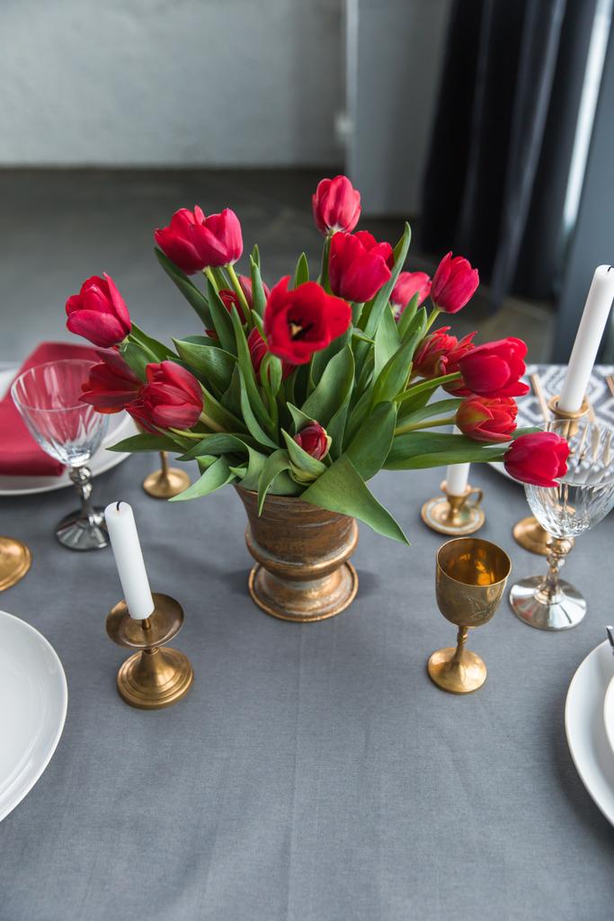 zblízka pohled kytice červené tulipány na desku stolu s uspořádány vintage příbory a svíčky - Fotografie, Obrázek