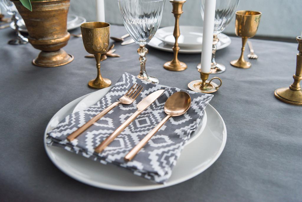vista de cerca de la mesa rústica con cubiertos antiguos y servilletas en platos, velas y copas de vino vacías en la superficie
 - Foto, imagen