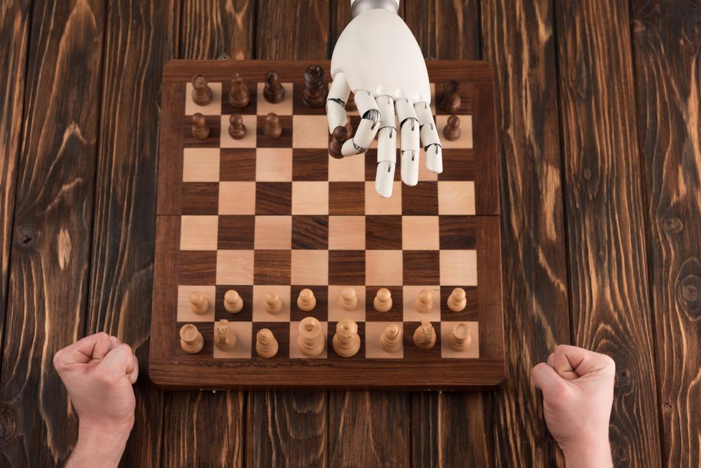 oříznuté shot robota hrát šachy s lidskými na dřevěný povrch - Fotografie, Obrázek