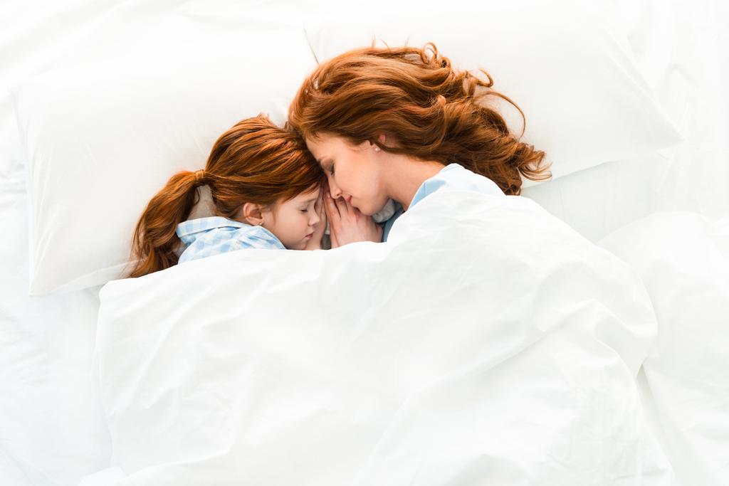 szép redhead anya és lánya együtt alszik az ágyban - Fotó, kép