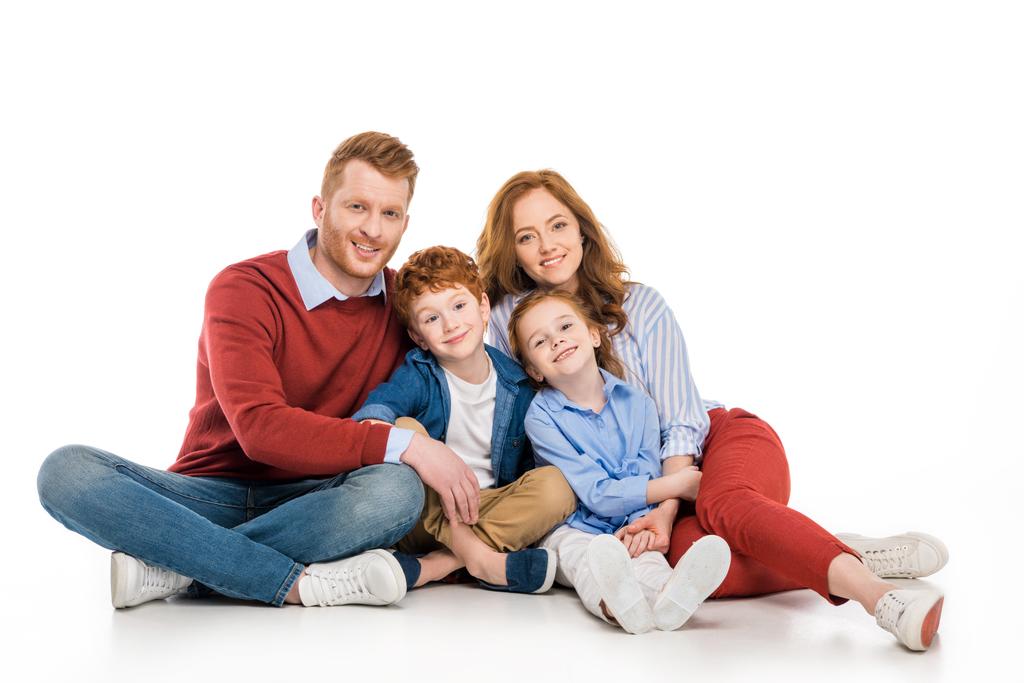 família ruiva feliz com dois filhos sentados juntos e sorrindo para a câmera isolada no branco
 - Foto, Imagem