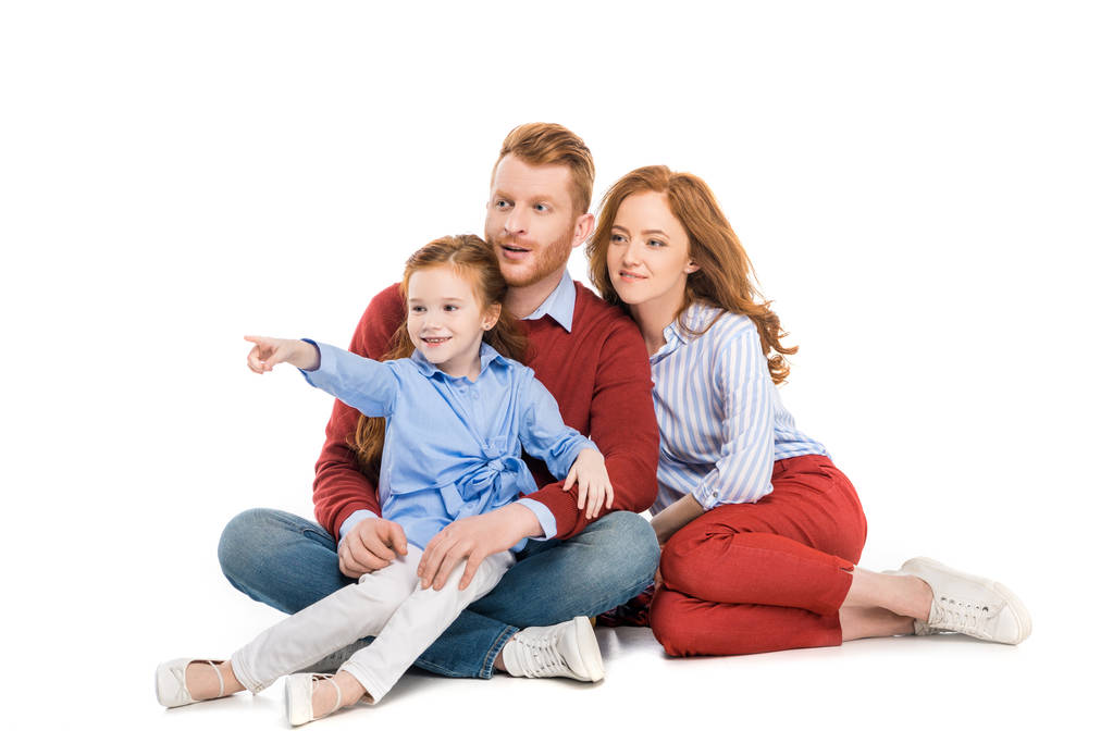 kaunis punapää perhe, jossa yksi lapsi istuu yhdessä ja katselee pois eristyksissä valkoisella
 - Valokuva, kuva