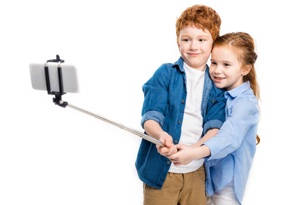 красиві щасливі руді діти беруть селфі зі смартфоном ізольовані на білому
 - Фото, зображення