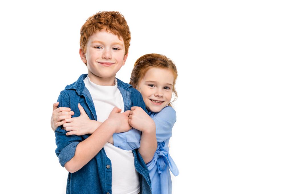 entzückende rothaarige Geschwister, die sich umarmen und in die Kamera lächeln - Foto, Bild