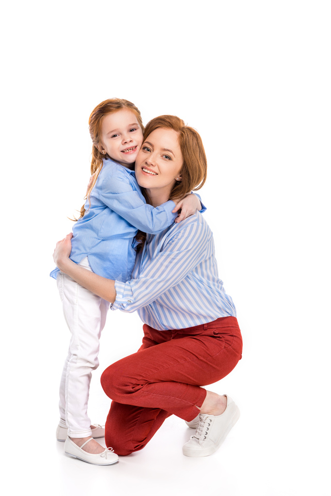 full length view of beautiful happy mother and daughter hugging and smiling at camera isolated on white  - Photo, Image