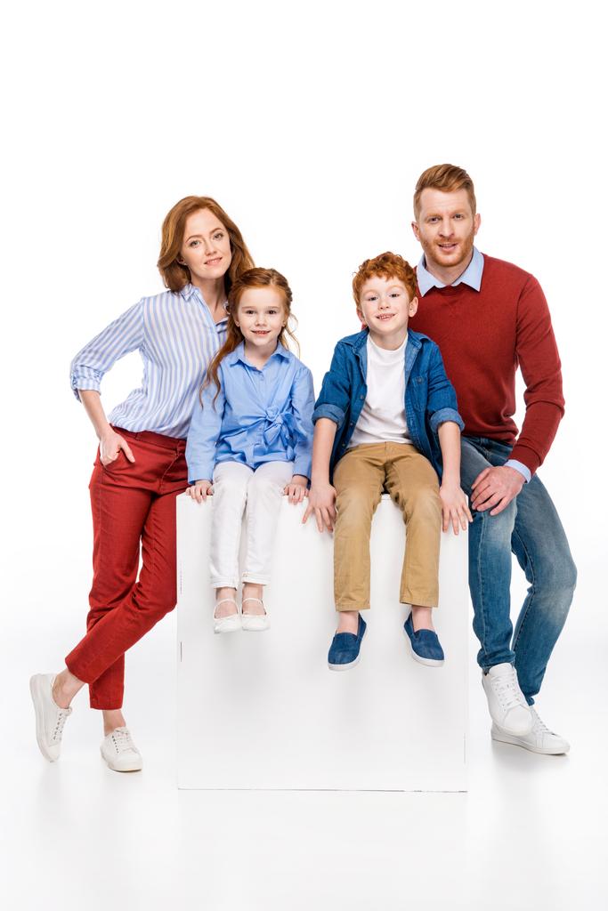 Gelukkig roodharige gezin met twee kinderen glimlachend op camera geïsoleerd op wit - Foto, afbeelding