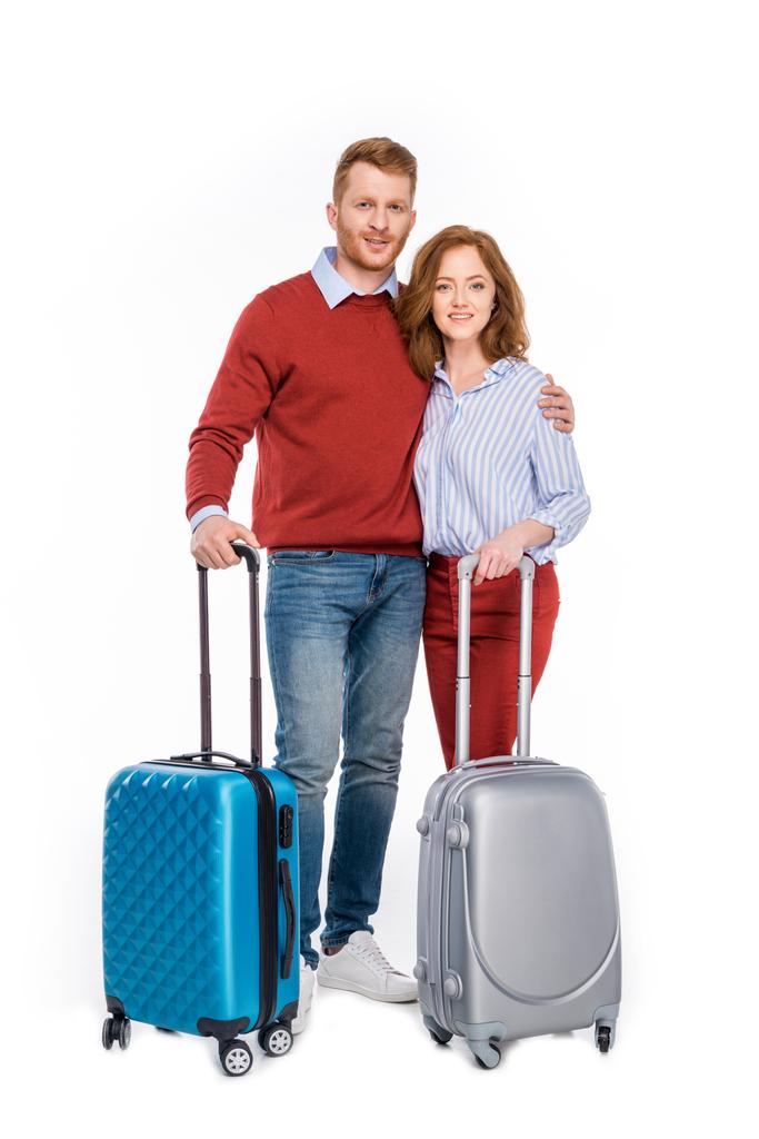 ευτυχισμένο ζευγάρι στέκεται με βαλίτσες και χαμογελαστός στην κάμερα που απομονώνονται σε λευκό - Φωτογραφία, εικόνα