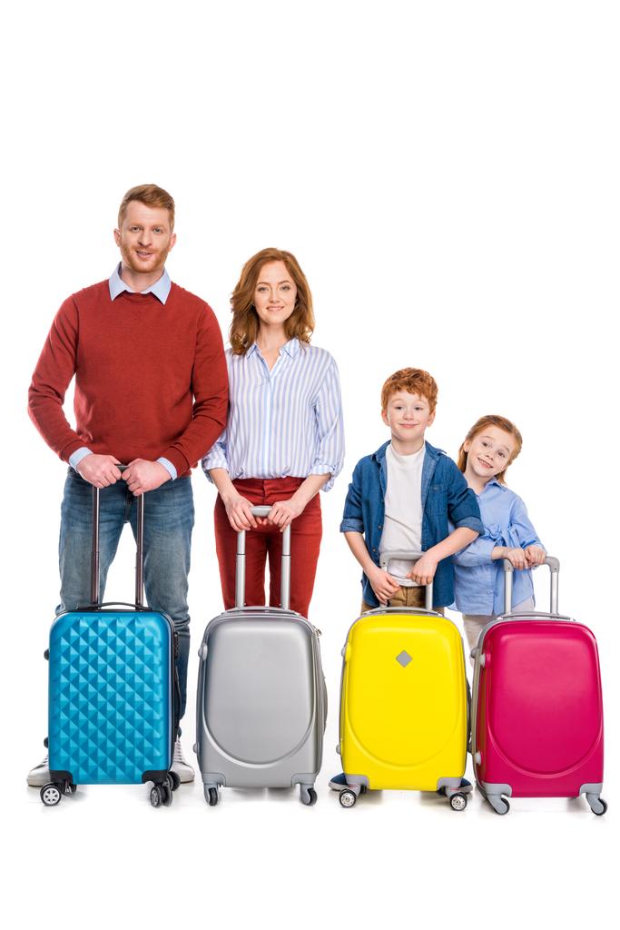 heureux rousse famille debout avec des valises colorées et souriant à la caméra isolé sur blanc
 - Photo, image