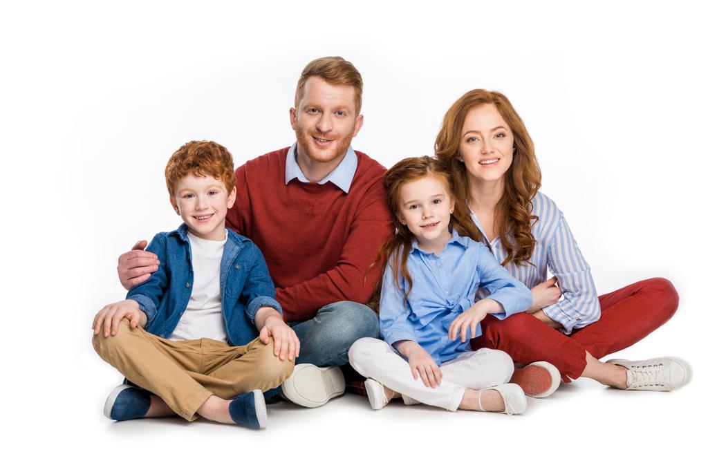 щаслива сім'я з двома дітьми, що сидять разом і посміхаються на камеру ізольовані на білому
 - Фото, зображення