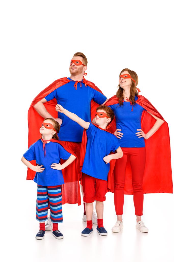 famille confiante de super-héros en masques et manteaux debout avec les mains sur la taille et regardant loin isolé sur blanc
 - Photo, image