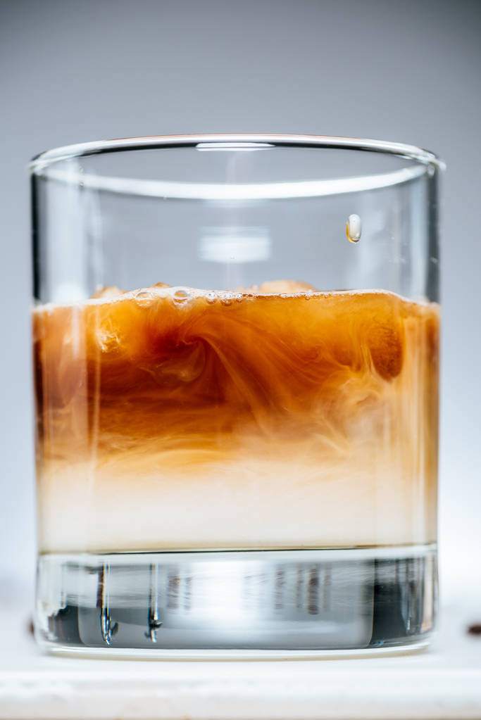 близкий вид холодного кофе со льдом с молоком в стакане на сером фоне
 - Фото, изображение