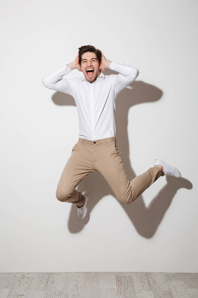 Täyspitkä kuva iloinen kaveri paita ja housut hyppääminen
  - Valokuva, kuva