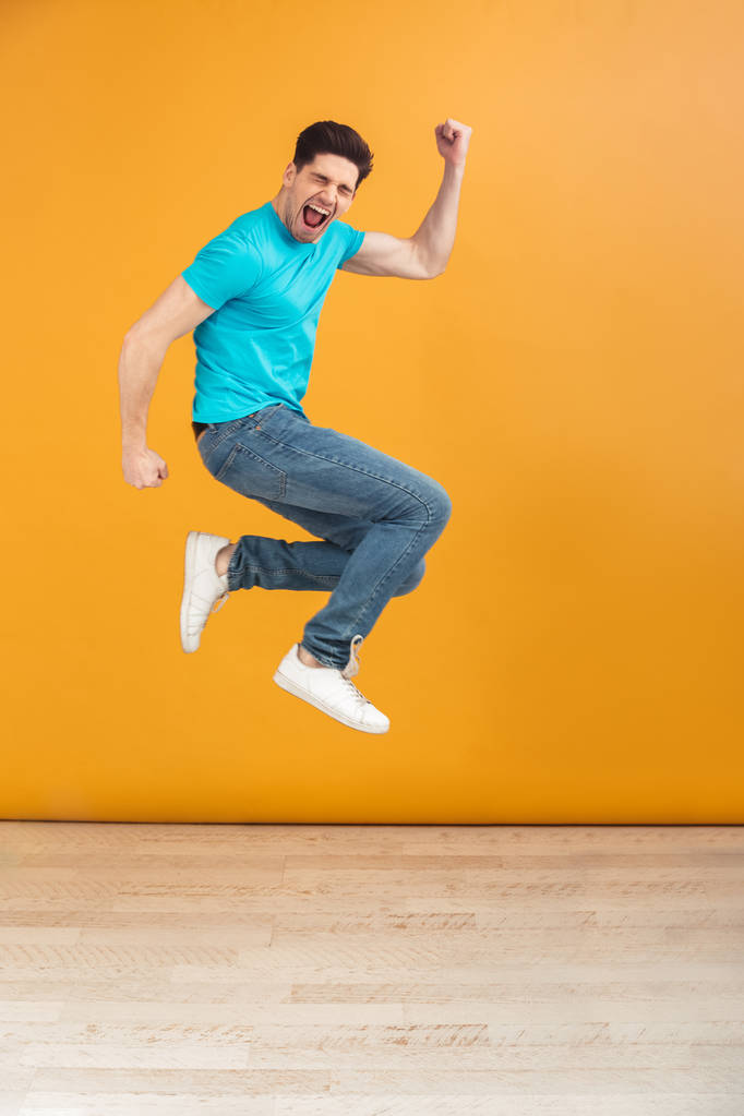 Volledige lengte portret van een tevreden jonge man springen - Foto, afbeelding