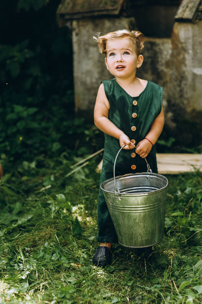 menino bonito brinca com um balde na grama
 - Foto, Imagem
