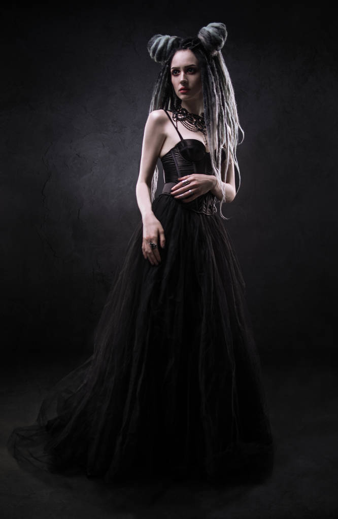 Γυναίκα με φόβους και μαύρο φόρεμα γοτθικό θέτοντας σε σκούρο φόντο - Φωτογραφία, εικόνα