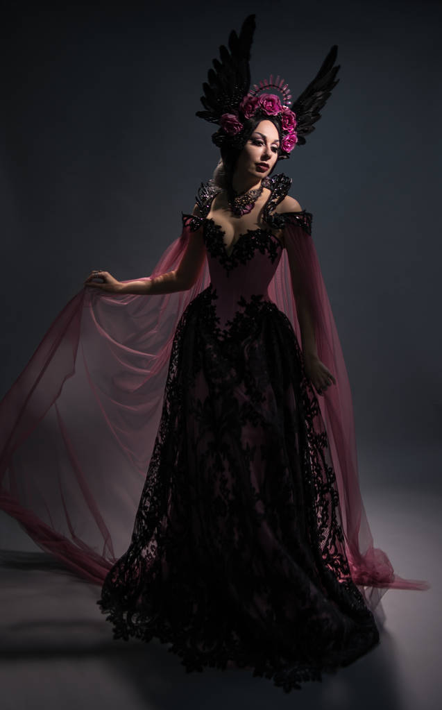 Ansicht der charmanten brünetten Frau in rosa Krone posiert auf dunklem Hintergrund in voller Länge - Foto, Bild