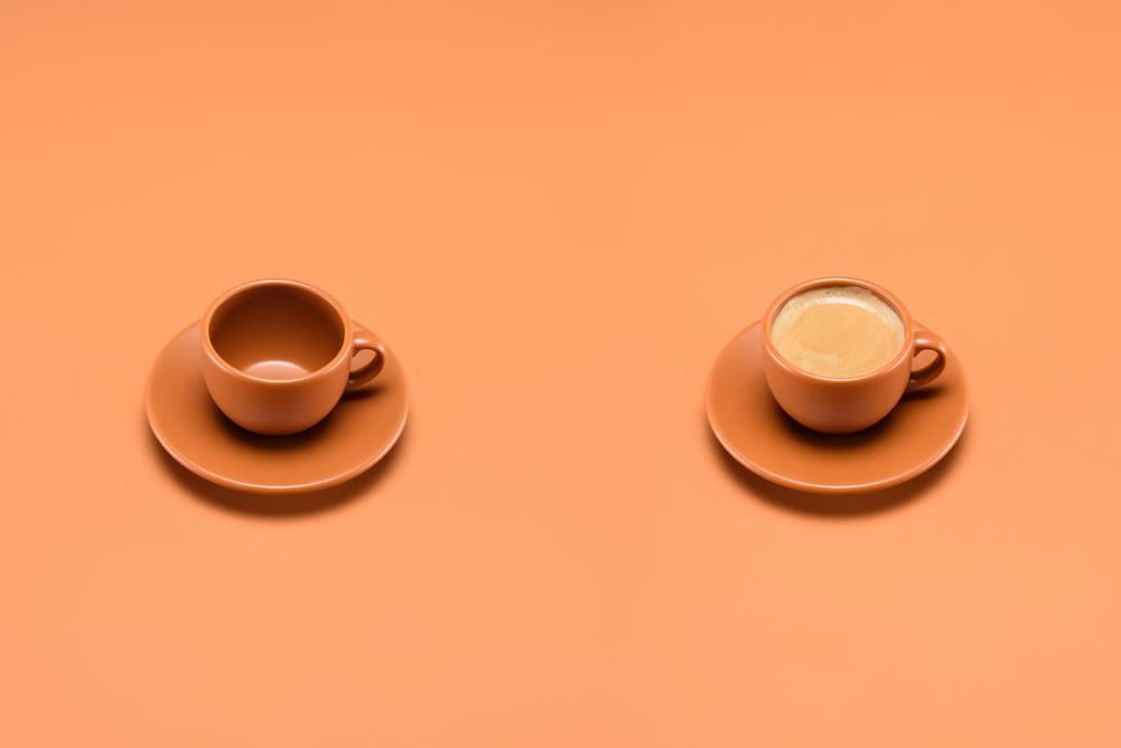 close up view of empty cup and cup of coffee isolated on peach - Photo, Image
