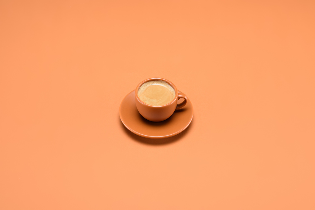 close up view of cup of coffee on saucer isolated on peach - Photo, Image