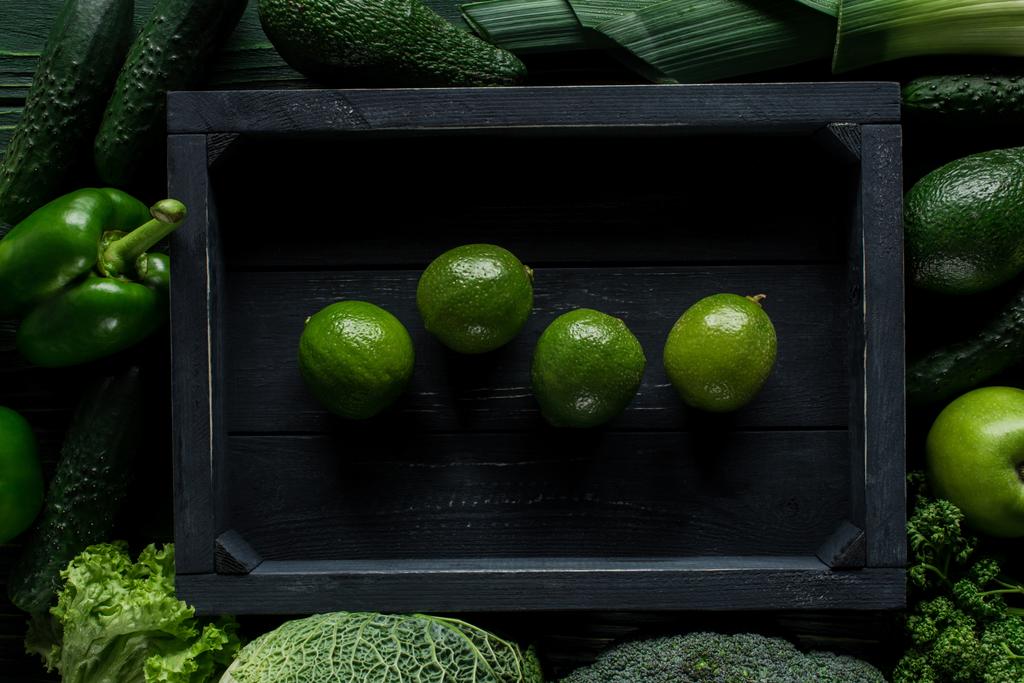 вид известь в деревянной коробке между зелеными овощами, концепция здорового питания
 - Фото, изображение