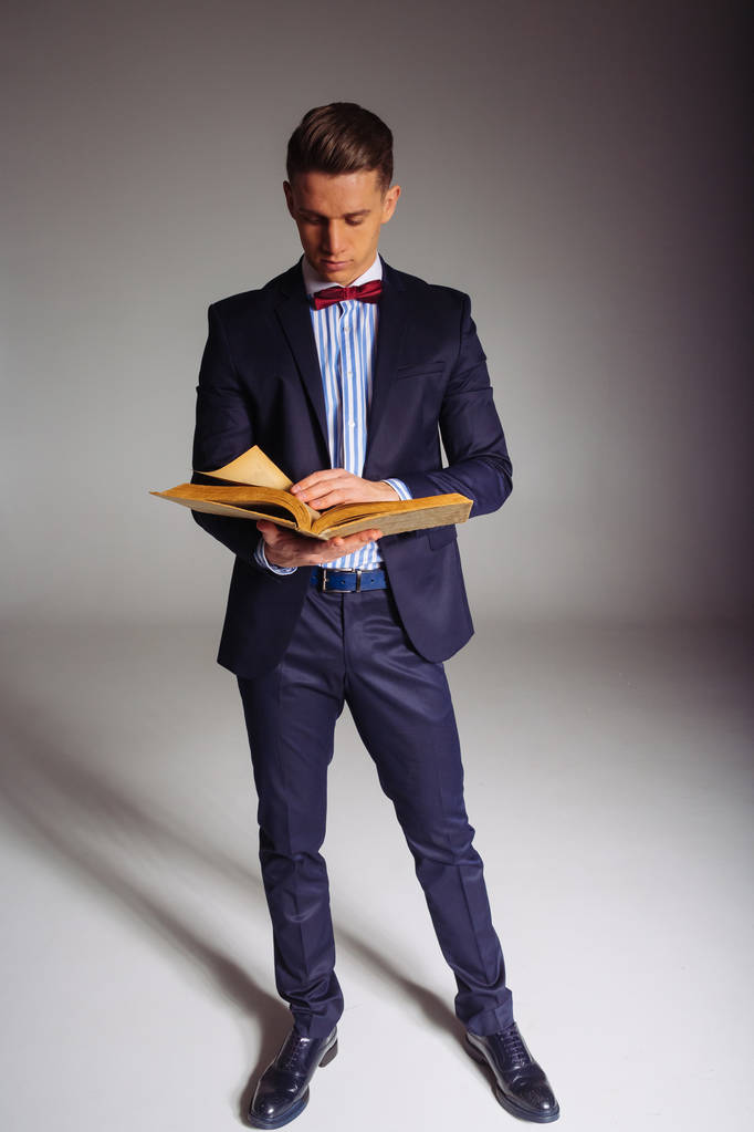 Человек, парень в синем костюме, стоит и читает старую книгу, концепцию знаний, учебы, науки, бизнеса, все новое, это хорошо забытое старое
 - Фото, изображение