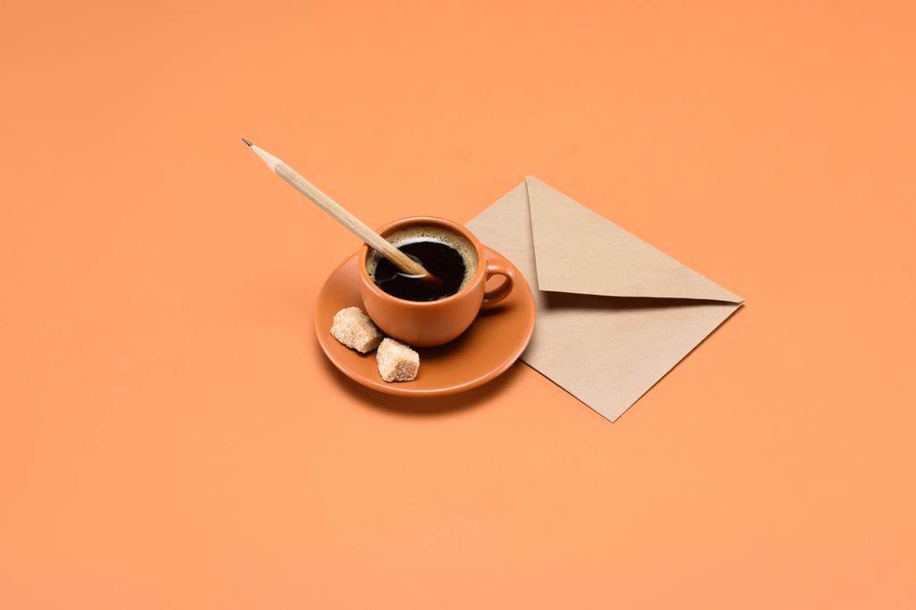 zblízka pohled na šálek kávy s tužkou, třtinový cukr na talíř a obálky poblíž izolované na broskev - Fotografie, Obrázek