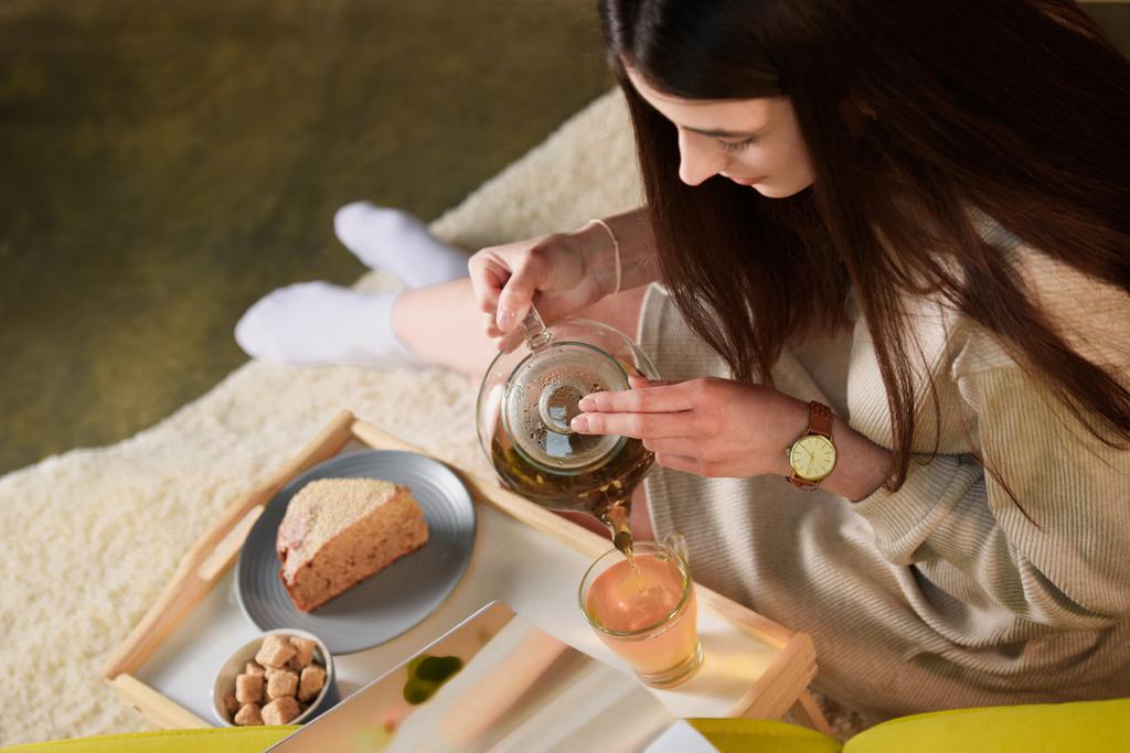 木製トレイ自宅にコップに熱いお茶を注いだ女性の高角度のビュー - 写真・画像