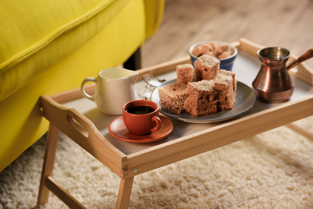 primer plano vista de la taza de café, jag de crema, trozos de pastel y azúcar morena en bandeja de madera en la habitación
 - Foto, imagen