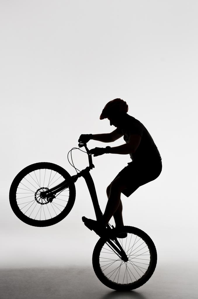 σιλουέτα του δοκιμή ποδηλάτης έλεγχοι που στέκεται στο πίσω τροχό σε λευκό - Φωτογραφία, εικόνα
