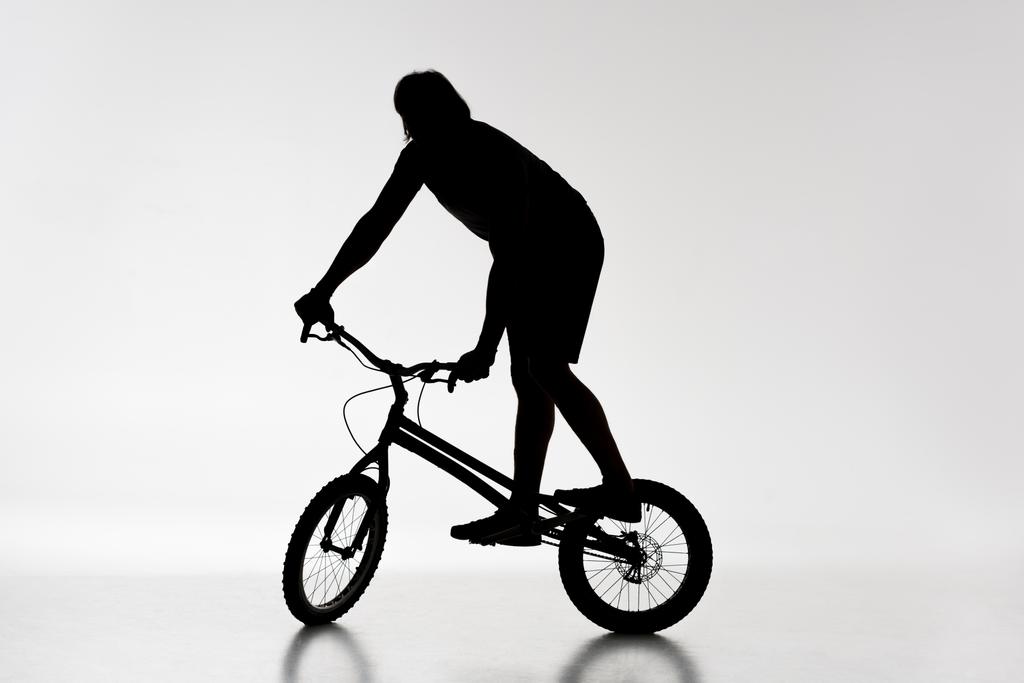silueta del motorista de trial balanceándose en bicicleta sobre blanco
 - Foto, imagen